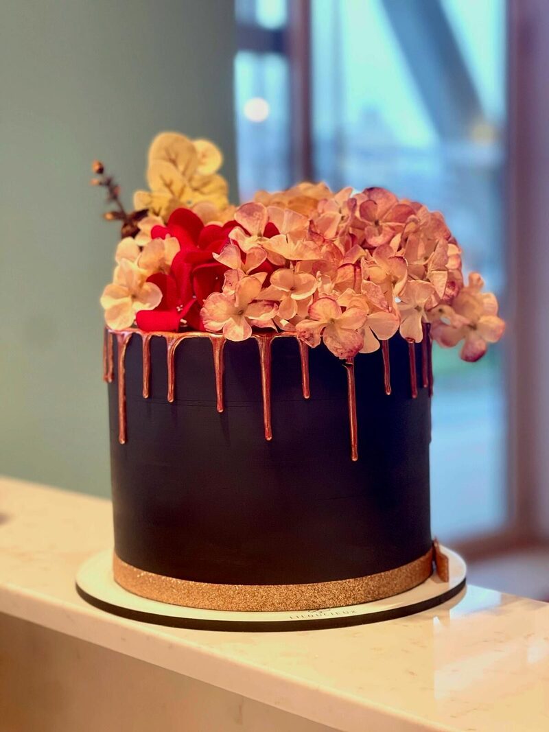 Gâteau au chocolat à coulure dorée surmonté d'hortensias