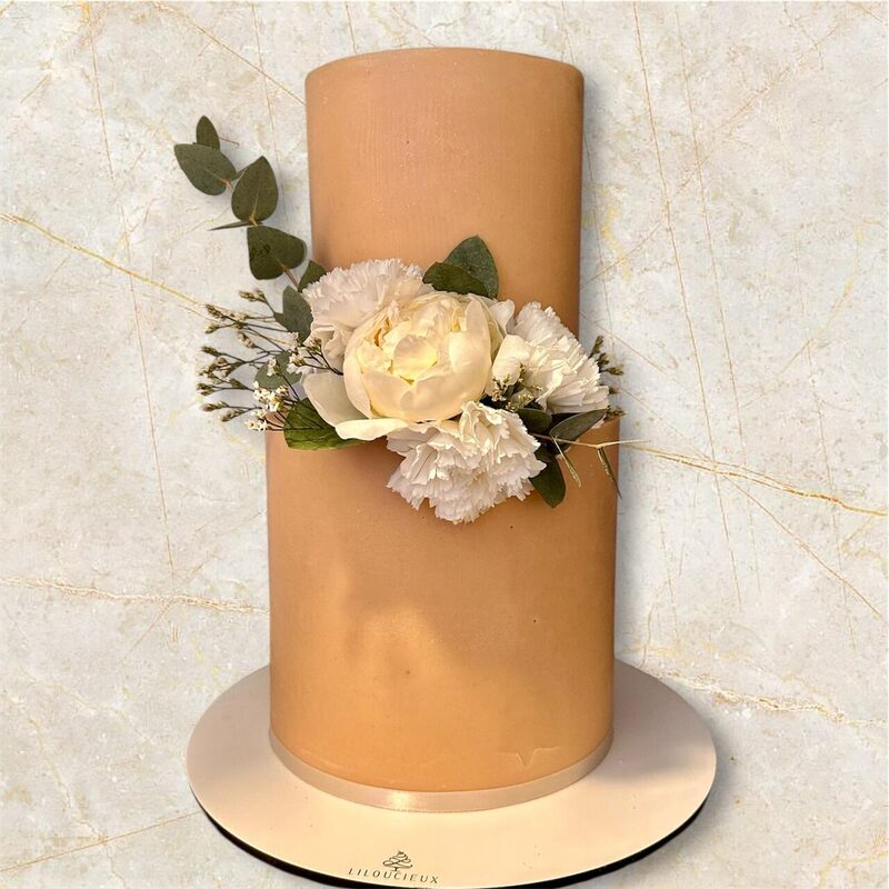 Gâteau doré caramel orné de fleurs blanches et d'eucalyptus